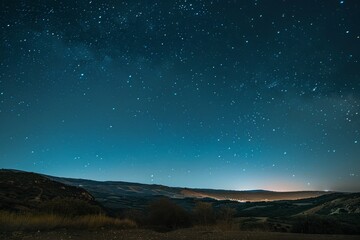 A wide-angle view of a star-filled night sky above a mountain range, showcasing the vast beauty of the universe
