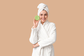 Happy young woman with hair scalp massager on brown background