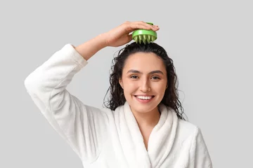 Gartenposter Beautiful young woman using hair scalp massager on grey background © Pixel-Shot
