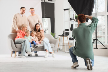 Male photographer taking picture of big family in studio, back view
