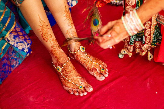 Bridal feet with henna tattoo during Haldi ceremony with peacock feather 