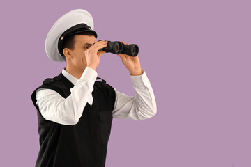 Young sailor looking through binoculars on lilac background