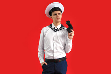 Young sailor with binoculars on red background