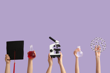 Female hands holding molecular model with filled flasks, microscope and graduation hat on lilac...