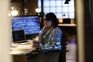 Female programmer working with tablet computer in office at night