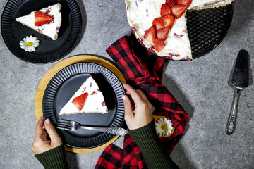 closeup hands holding a strawberry cake or Fraisier in french language in black plate  on grunge...