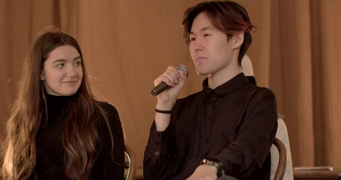 Person in club to improve public speaking, presentation. Debate Clubs background. Asian Man practice presenting arguments into microphone. Communication development and speech improvement of people.