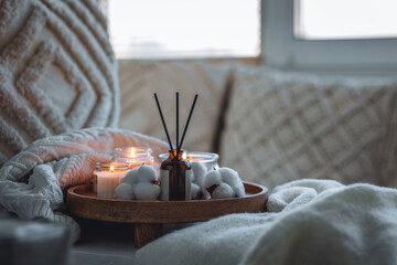 Burning aroma candle and reed diffuser with gentle delicate cotton flower scent. Home aromatherapy, cozy composition for bedroom. Detention, meditation, relaxation. Concept of wellbeing, wellness