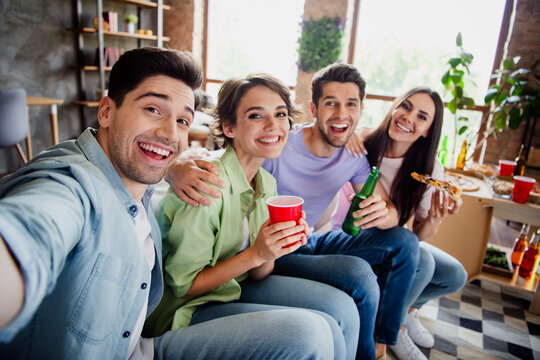 Photo of idyllic positive buddies sitting couch hug drink beer eat pizza make selfie daylight house indoors