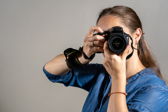 Mujer fotógrafa tomando una fotografía apuntando su cámara al espectador