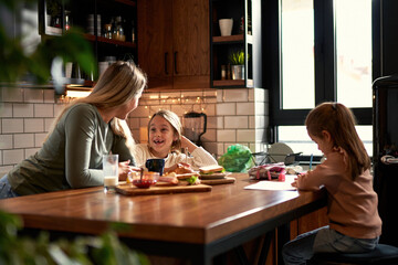 Mother and two daughters share the kitchen table, with mom and the elder sister working on homework...