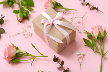 Beautiful wrapped gift box with spring flowers on pink background