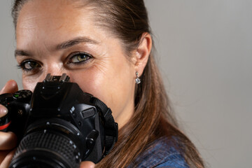 Mujer fotógrafa profesional usando su cámara y mirando a cámara con expresión de confianza
