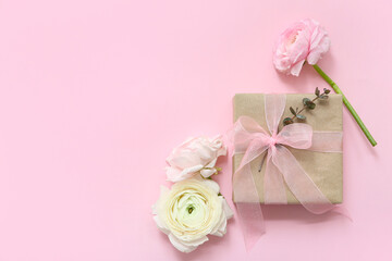 Wrapped gift box with flowers on pink background