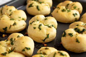 Homemade Garlic Knots with Parsley on a Baking Tray, side view.