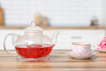 Teapot and cup of hibiscus tea on table in kitchen
