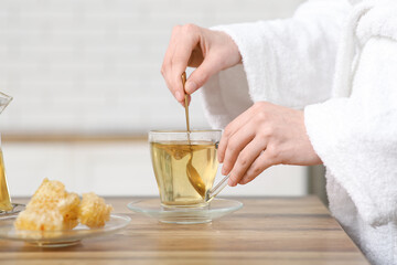 Young woman stirring green tea in kitchen