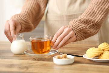 Young woman making tea with milk in kitchen
