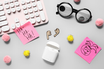 Carton earphones, sticky notes, computer keyboard and funny glasses on white background. April Fools Day prank