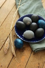 colored Easter eggs in a blue bowl an a wooden table
