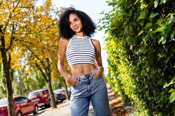 Obraz premium Photo of gorgeous shiny adorable girl wearing stylish outfit with hands in pockets enjoying amazing weather outside