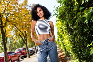 Foto op Plexiglas Photo of gorgeous shiny adorable girl wearing stylish outfit with hands in pockets enjoying amazing weather outside © deagreez
