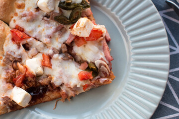 Slices of pizza with cheese with bell pepper and meat on a plate.