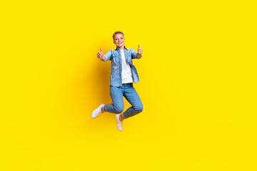 Fototapeta na wymiar Full body photo of attractive young woman jumping show thumb up good quality wear trendy jeans clothes isolated on yellow color background