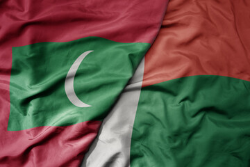 big waving national colorful flag of madagascar and national flag of maldives .