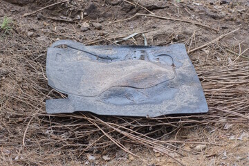 one dirty rubber black car mat lies on the gray ground on the street