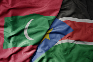 big waving national colorful flag of south sudan and national flag of maldives .