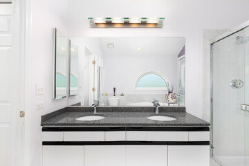 A bathroom with a white and black cabinet, grey marble countertop, and tiled shower and bathtub.