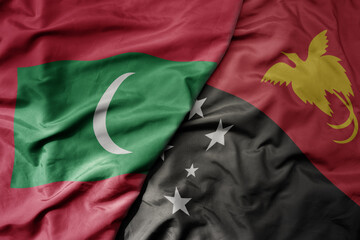 big waving national colorful flag of Papua New Guinea and national flag of maldives .