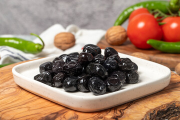 Black olive. Delicious olives grown in the Mediterranean region on a wooden serving board. Close up