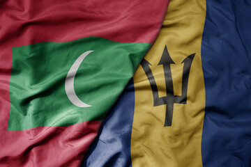 big waving national colorful flag of barbados and national flag of maldives .