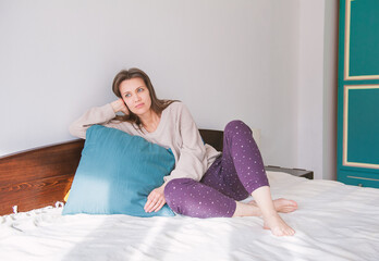 Happy woman sitting on the bed and relaxing at home