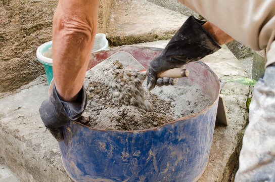 man bricklayer mixing cement with sand with trowel, to make concrete. Latin America.