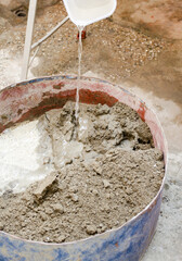 Water falling on cement and sand mixture in container for architectural construction work.