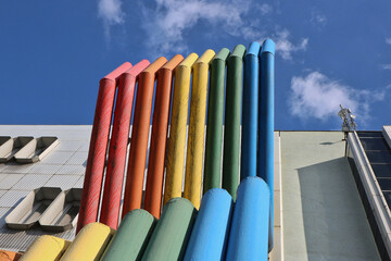 Colorful painted metal pipes lined up next to each other as a design decoration in front of a historic building in high-tech style on the background