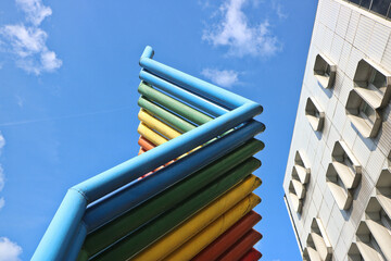Colorful painted metal pipes lined up next to each other as a design decoration in front of a historic building in high-tech style on the background