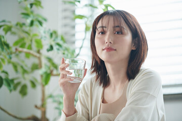 ベッドで水を飲む20代女性