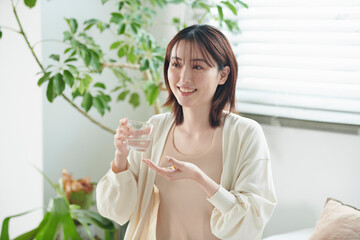 ベッドでサプリを飲む20代女性