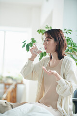 ベッドでサプリを飲む20代女性