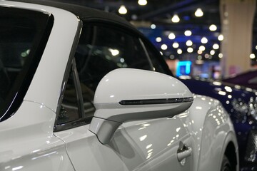 A side mirror of a white convertible car