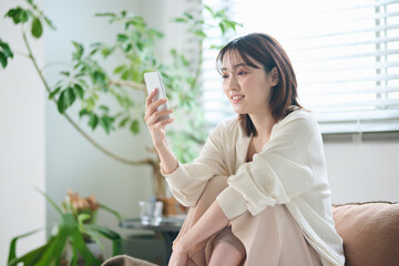 ベッドでスマートフォンを見る20代女性
