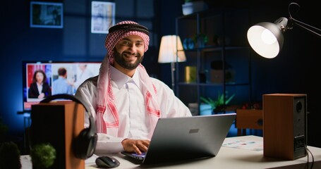 Happy arabic teleworker answering job emails in stylish apartment. Cheerful muslim employee...