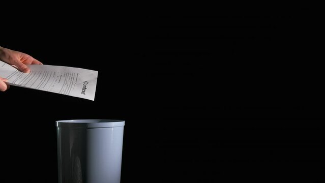 Business trash contracts on black background. A view of woman throw the business trash documents into bin on the black background.