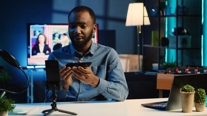 African american technology content creator filming review of newly released smartphone, greeting...