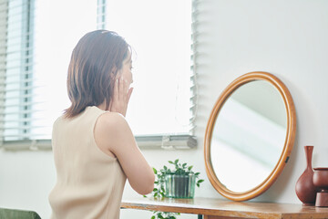 鏡の前でスキンケアをする20代女性