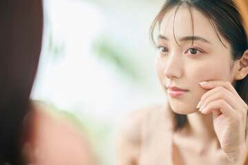 自分の肌に触れる20代女性,反射,鏡